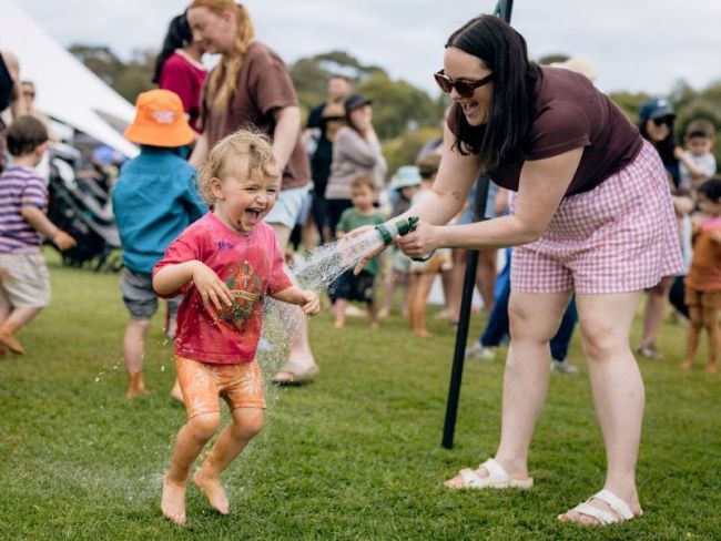 Young child laughing while being sprayed with water