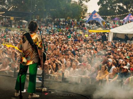 Singer with guitar facing out to large crowd