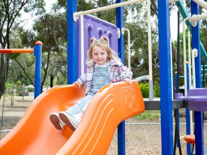 Young child sitting at the top of a playground slide