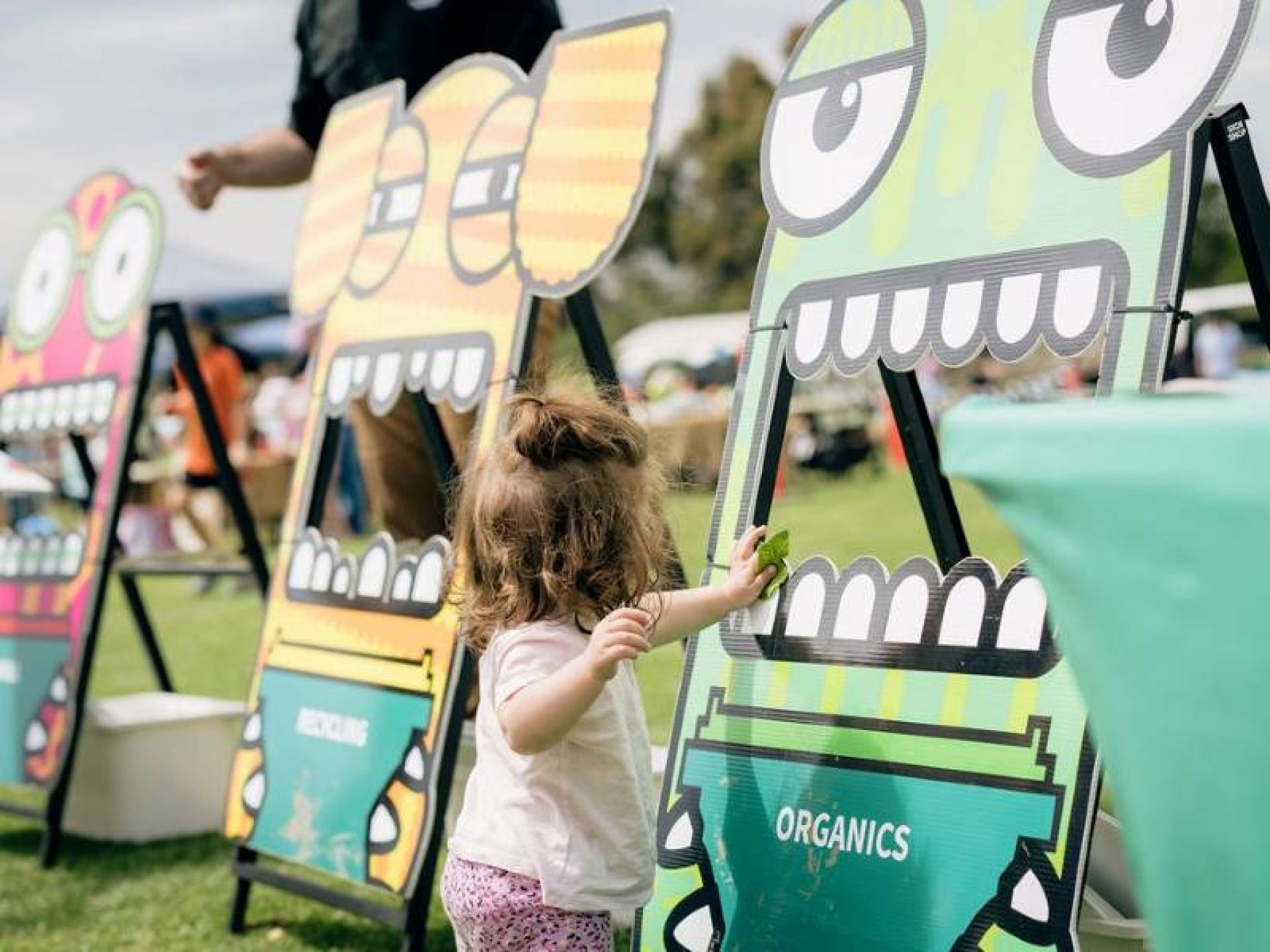 Young child placing correct litter into a green waste bin