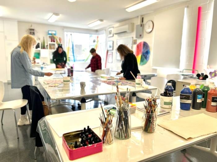 Four people in a room with painting supplies creating art