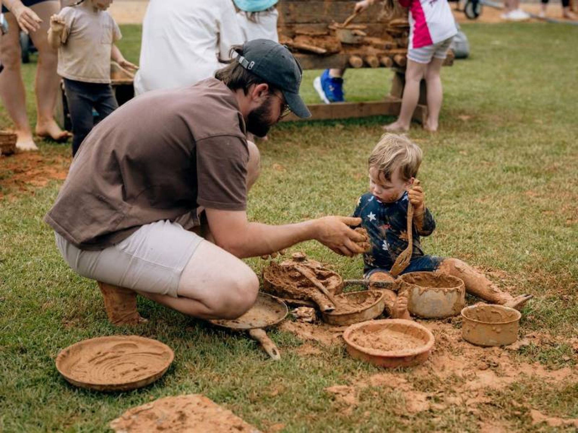 Young boy playing with pots and pans in the mud