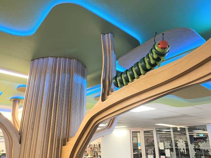 Wooden tree designed column with a large caterpillar decoration