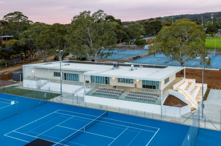 Tennis club building with tiered spectator seating and blue tennis courts