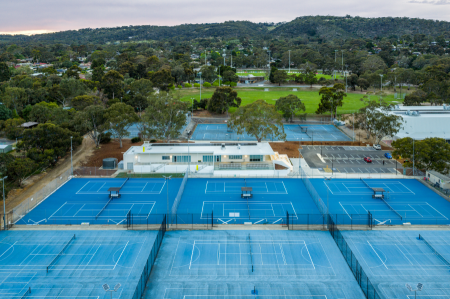 Aerial view of tennis club building surrounded by multiple tennis courts and car park